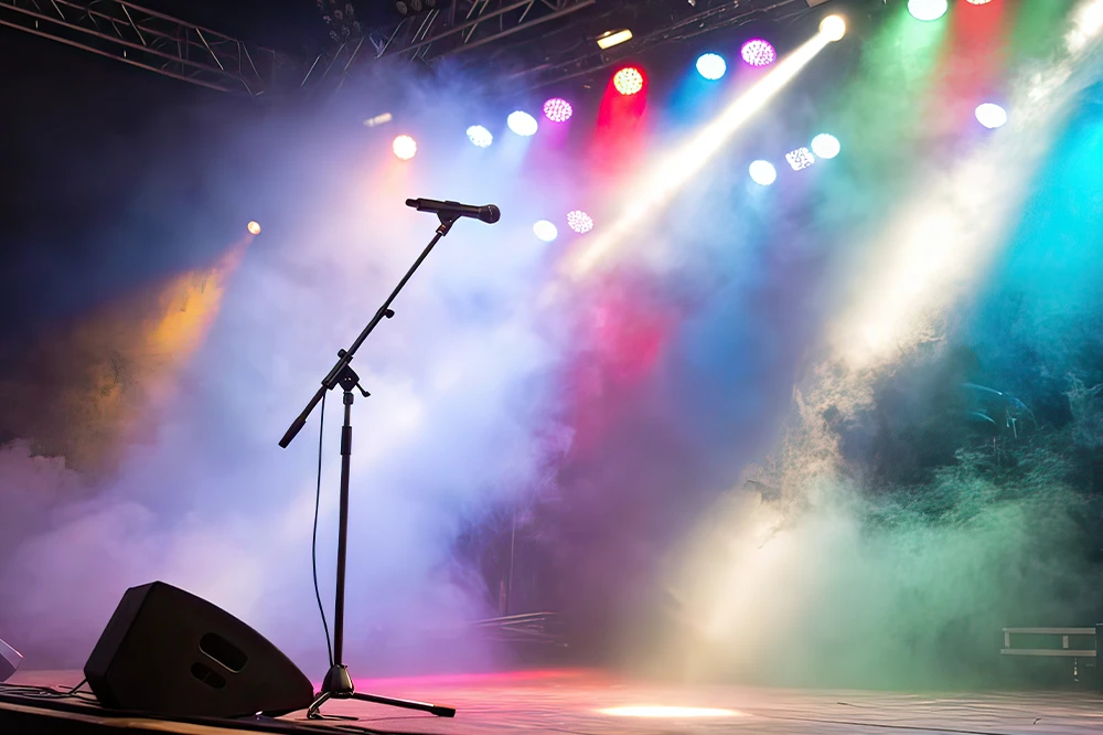 Microphone stand on a fog-filled stage under colourful stage lighting