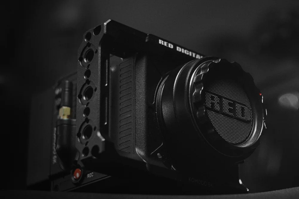 Close-up of the RED Komodo 6K digital cinema camera body with lens cap, captured in dramatic low light