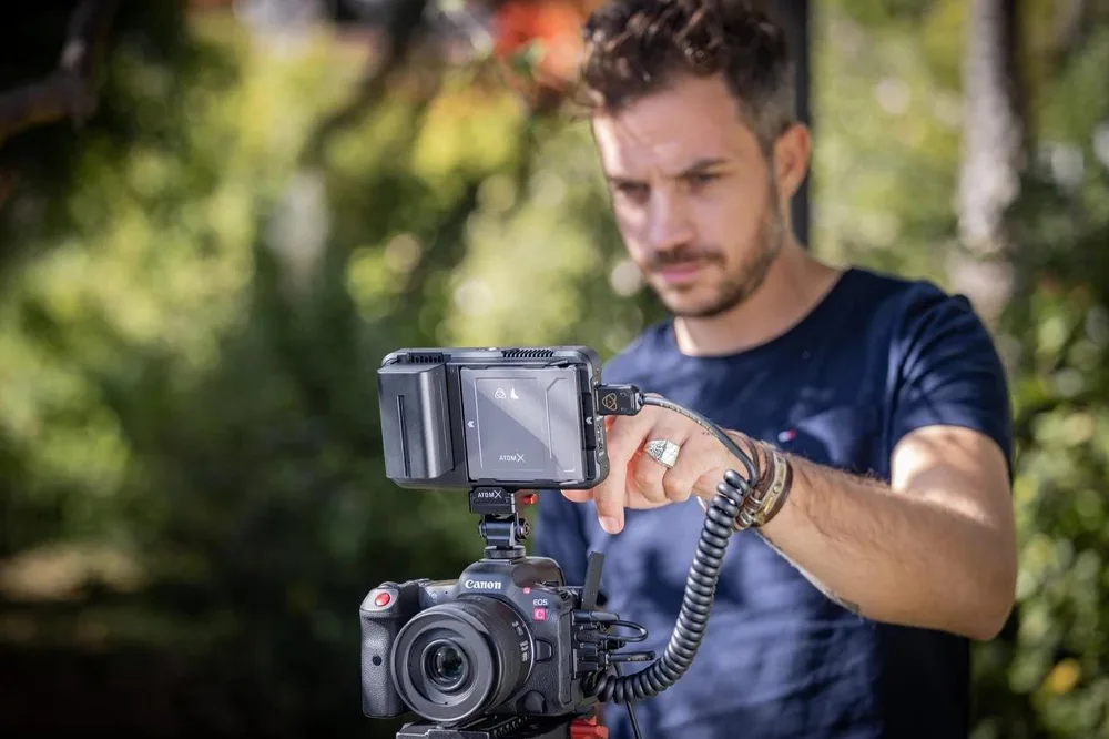 Canon mirrorless video camera with screen open and rigged for filming